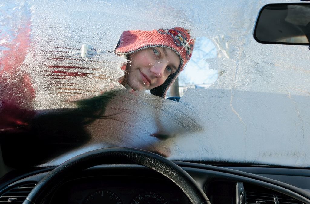 Frau kratzt Eis von ihrer Autoscheibe