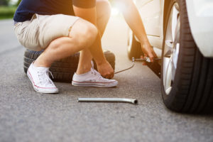 Ein Mann wechselt den Reifen eines Autos (Autoreifen selber wechseln).