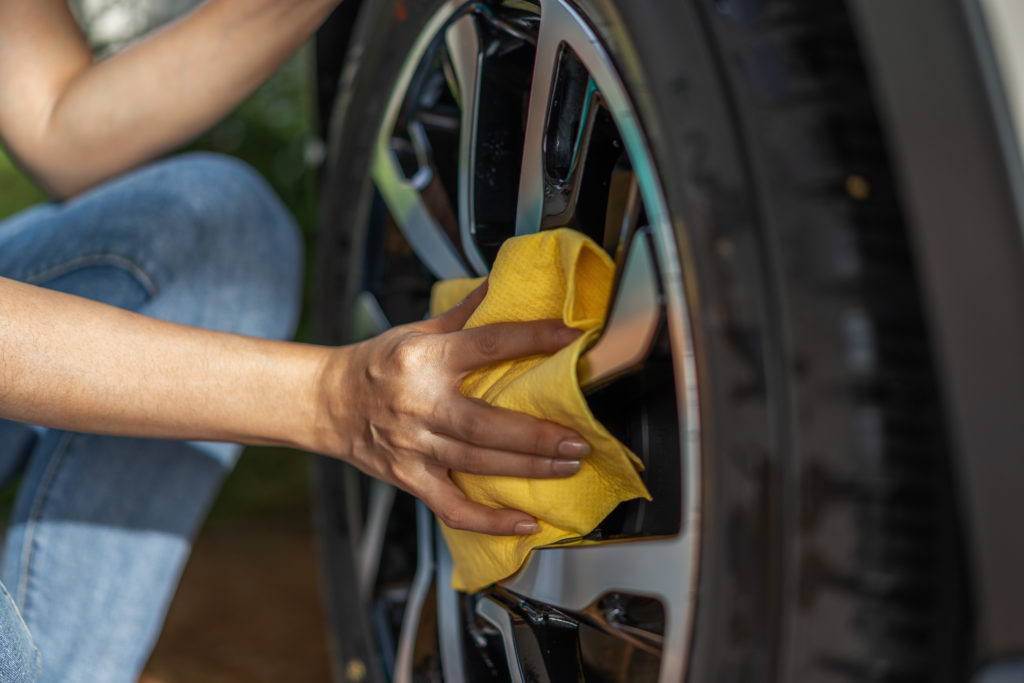 Autopflege im Frühjahr: Autoreifen werden mithilfe eines gelben Tuches gesäubert.